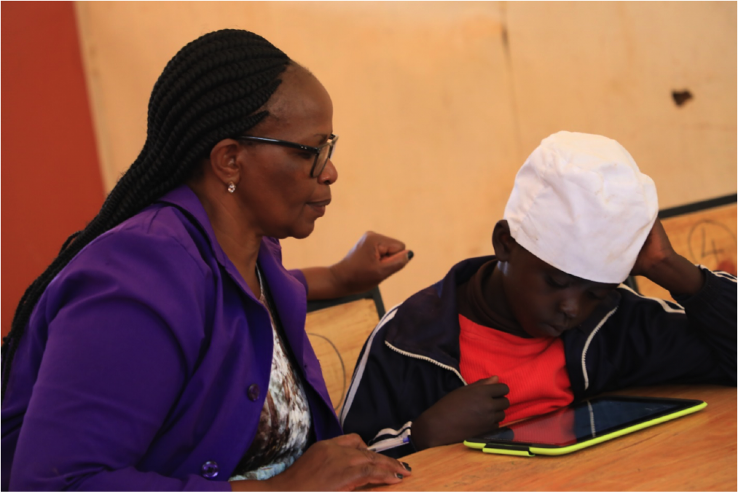 Teacher Jane Njoroge looks on as Frank from Mugumoini Primary School in Thika Town uses his digital tablet