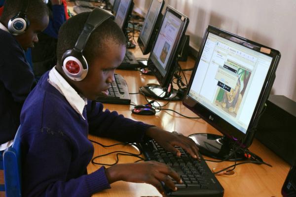 A student with headphones uses a desktop computer